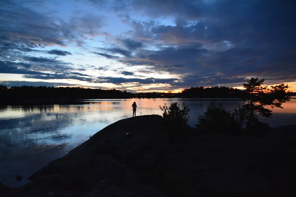 A person standing on a rock near a body of water.