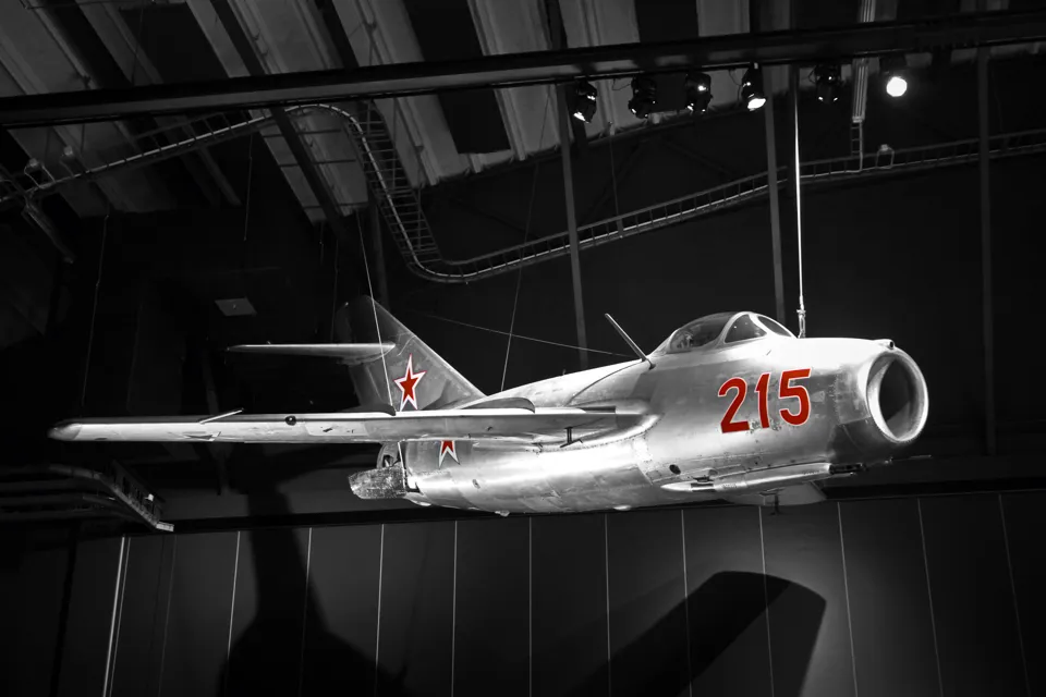 A fighter jet suspended from the ceiling of a hangar.
