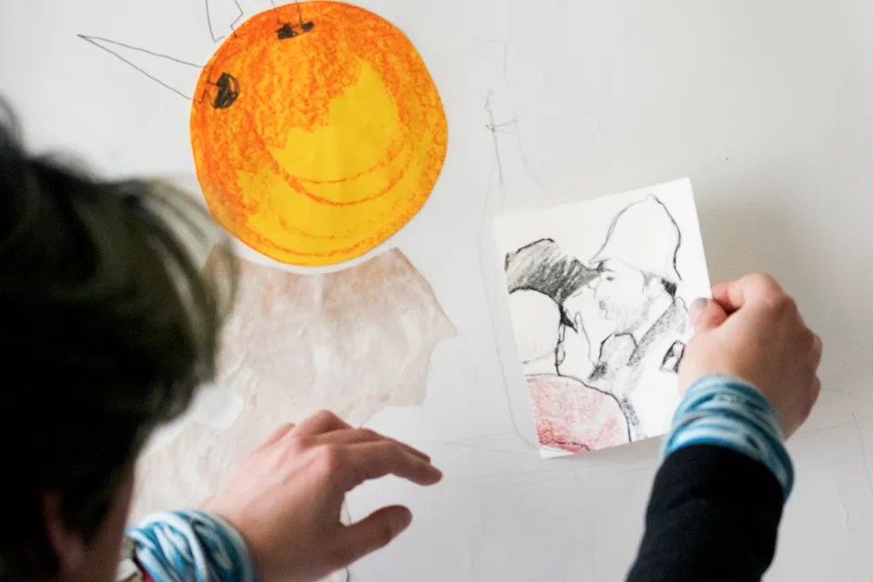 En person ritar ett leende ansikte på en vägg.
