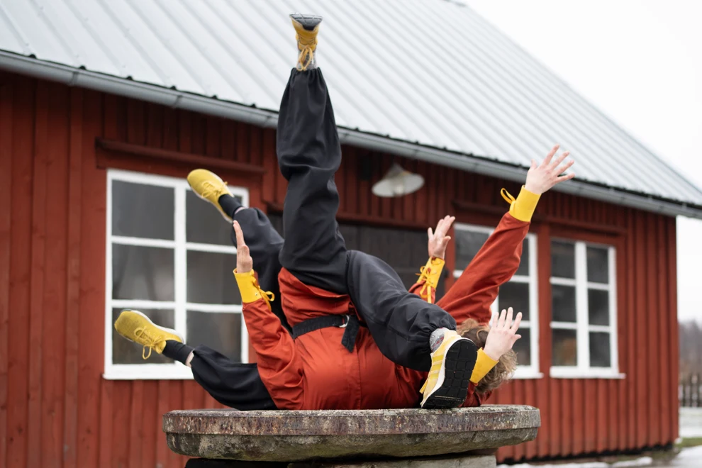 Personer som dansar på en bänk framför en röd byggnad.