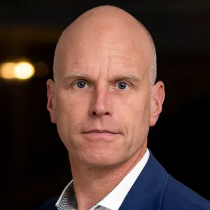 En man i blå kostym som står i en korridor.