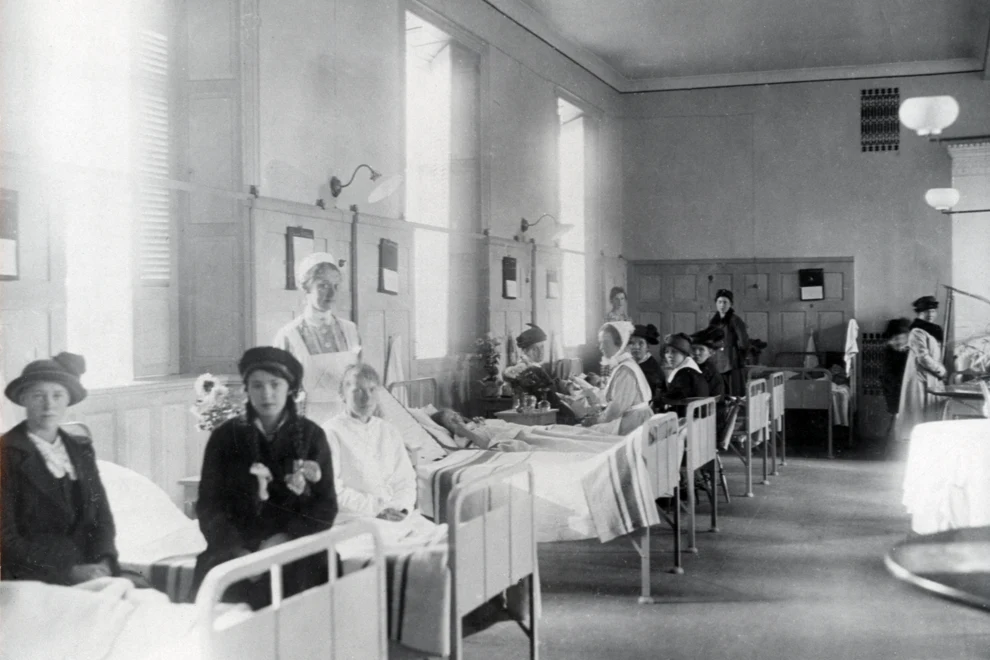Sjuksal från Strömbacken med sjukhussängar och vårdpersonal i ett stort rum.