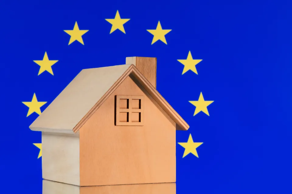 Ett trähus med en EU-flagga i bakgrunden.