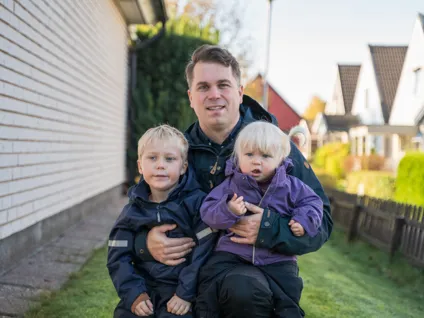 En man som sitter på en bänk med två barn.