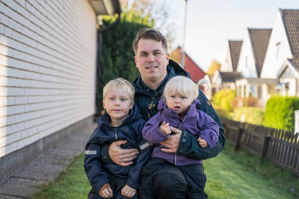 En man som sitter på en bänk med två barn.