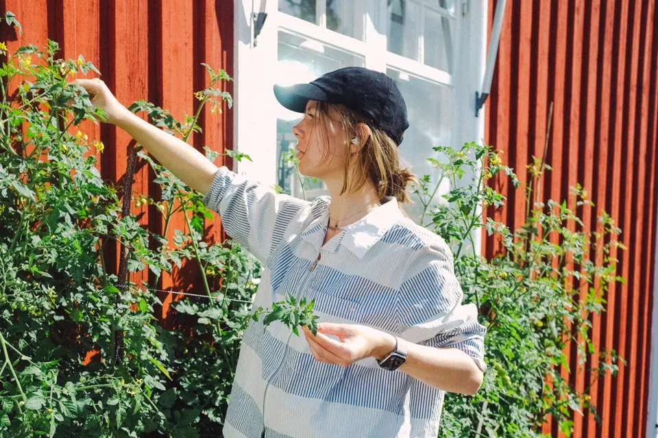 A woman standing in front of a bunch of plants.