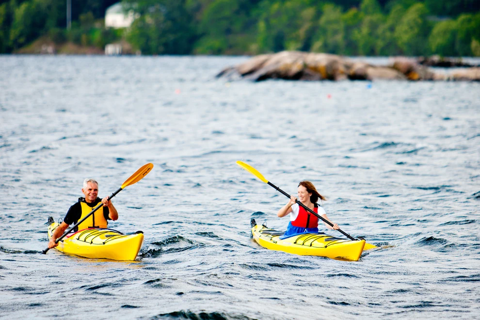 Two people in kayaks paddling on a lake.