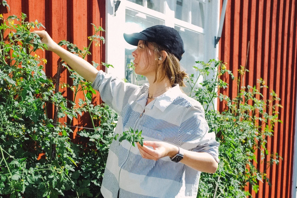A woman standing in front of a bunch of plants.