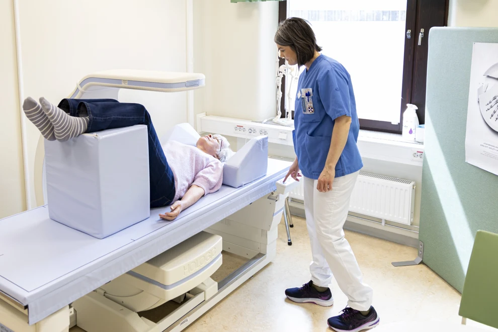 Sjuksköterska vid osteoporosmottagningen  som mäter bentäthet hos patient.