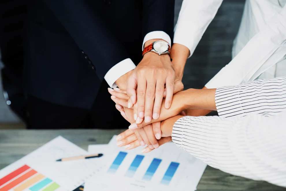 En grupp människor som håller varandra i handen över några papper.
