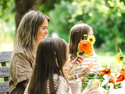 En grupp kvinnor som sitter runt ett bord med blommor.